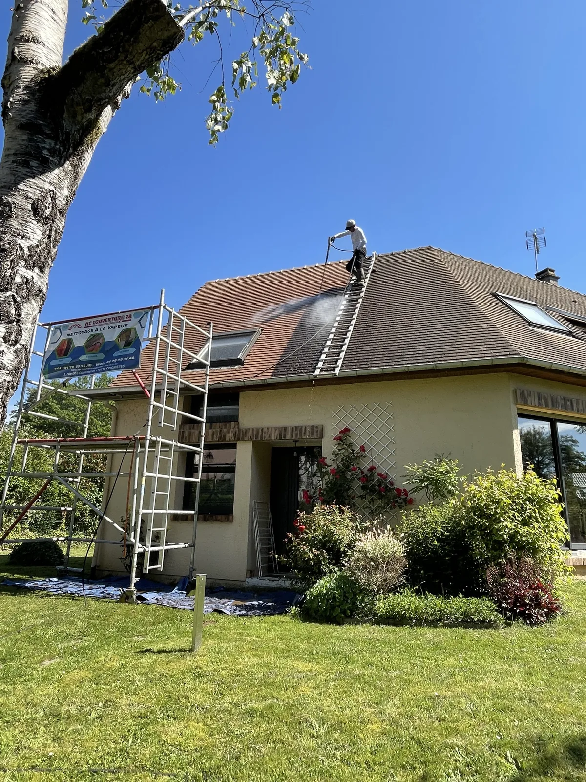 Opérateur sur une toiture appliquant de la vapeur, avec de la végétation autour du chantier